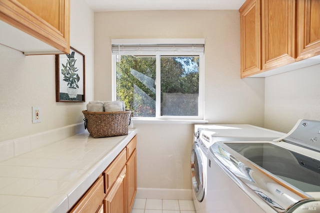 laundry area with baseboards, cabinet space, washing machine and clothes dryer, and light tile patterned floors