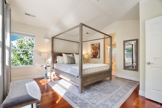 bedroom with vaulted ceiling, wood finished floors, visible vents, and baseboards