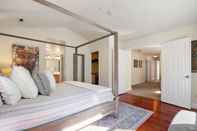 bedroom featuring lofted ceiling, ensuite bath, wood finished floors, and baseboards