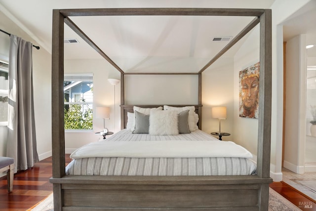 bedroom featuring wood finished floors, visible vents, and baseboards