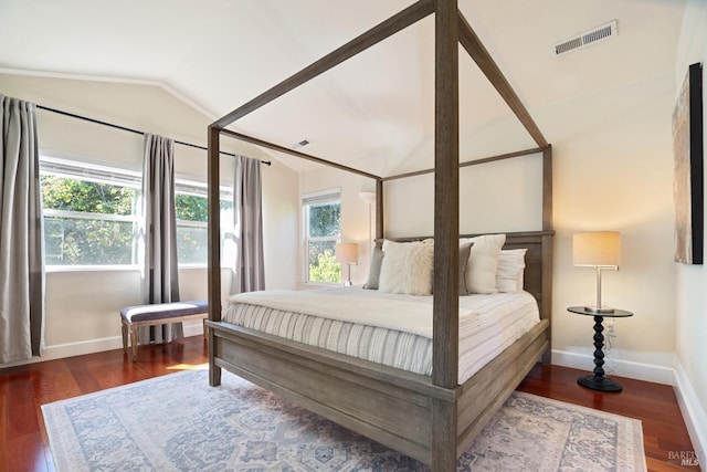 bedroom with baseboards, visible vents, vaulted ceiling, and wood finished floors