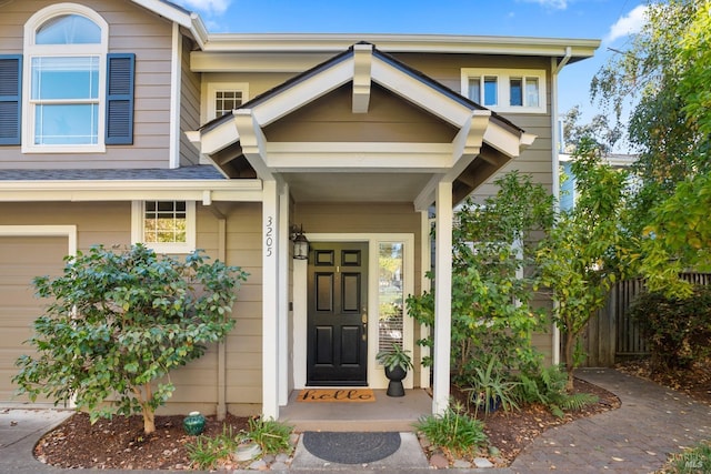 view of exterior entry featuring a garage and fence