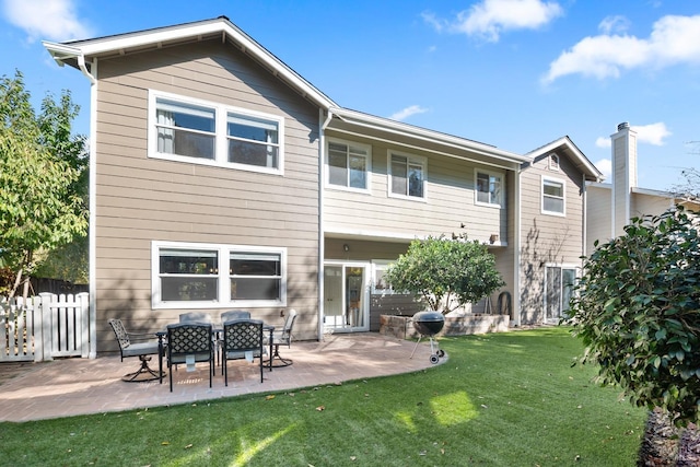 back of property with fence, a lawn, and a patio