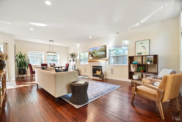 living area with baseboards, dark wood finished floors, a tiled fireplace, and recessed lighting