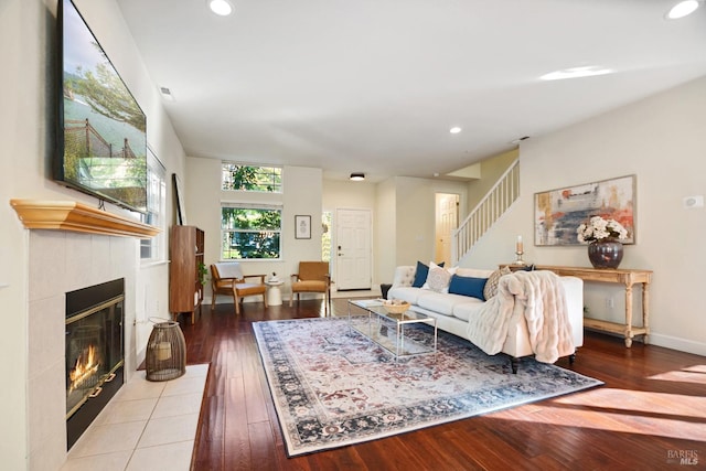 living room featuring stairway, a tiled fireplace, wood-type flooring, and recessed lighting