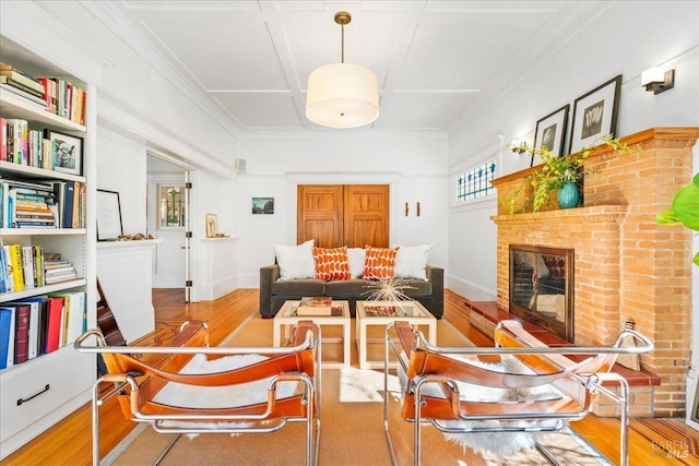 interior space with ornamental molding, a brick fireplace, baseboards, and wood finished floors