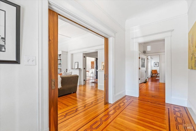 hallway with baseboards, light wood-style flooring, and crown molding