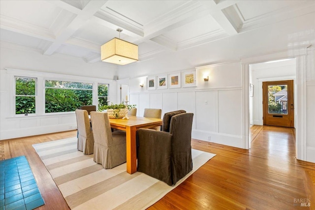 dining room featuring a decorative wall, coffered ceiling, wainscoting, beam ceiling, and light wood finished floors