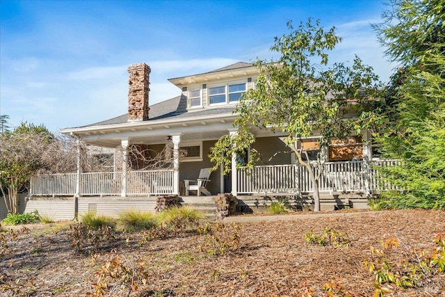 back of property featuring covered porch and a chimney