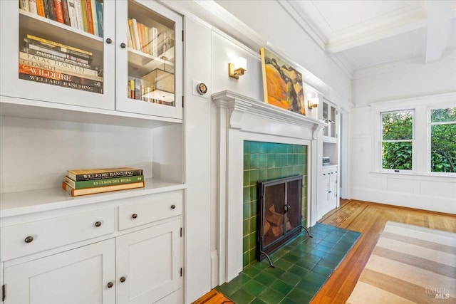 interior space with ornamental molding, beam ceiling, a fireplace, and wood finished floors