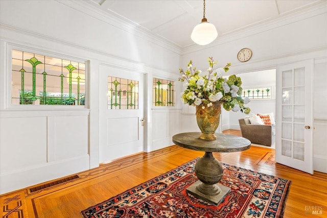 interior space with french doors, visible vents, a decorative wall, ornamental molding, and wood finished floors