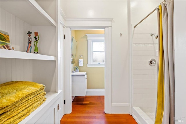 bathroom with a shower stall, baseboards, wood finished floors, and vanity