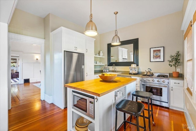 kitchen featuring appliances with stainless steel finishes, white cabinets, dark wood-type flooring, and open shelves