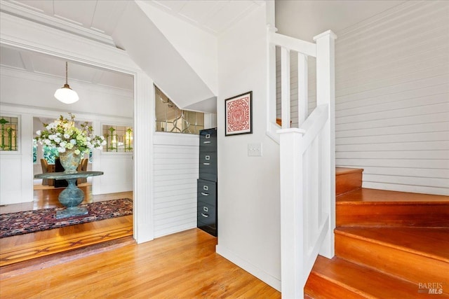 stairs featuring ornamental molding and wood finished floors