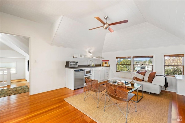 living room with lofted ceiling, light wood finished floors, a ceiling fan, and baseboards