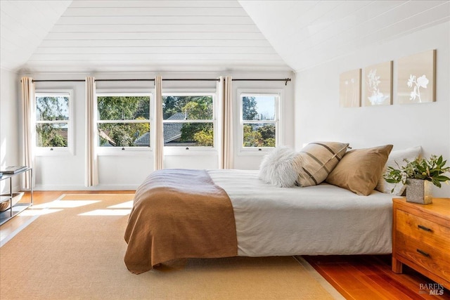 bedroom with vaulted ceiling, multiple windows, and wood finished floors