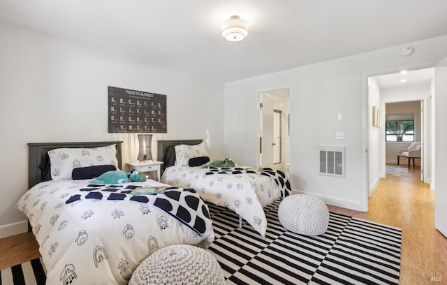 bedroom featuring visible vents, baseboards, and wood finished floors