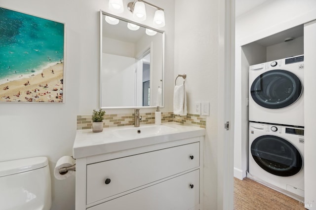 bathroom with toilet, backsplash, stacked washer / dryer, and vanity