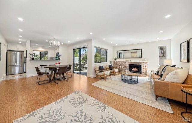 living room with a brick fireplace, baseboards, wood finished floors, and recessed lighting