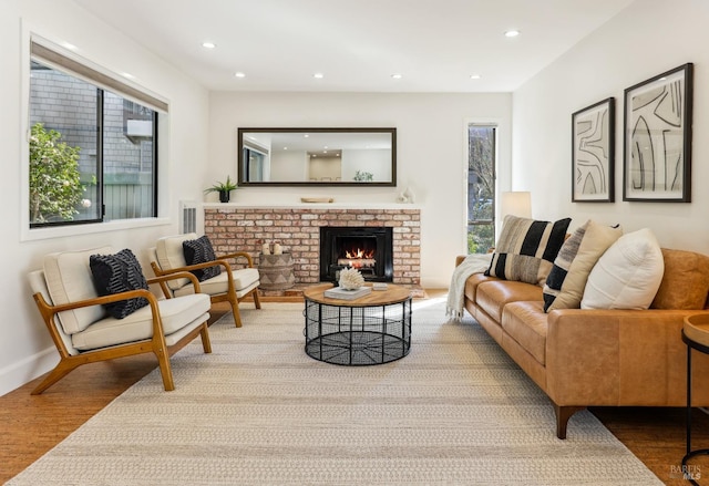 living area with recessed lighting, a brick fireplace, baseboards, and wood finished floors