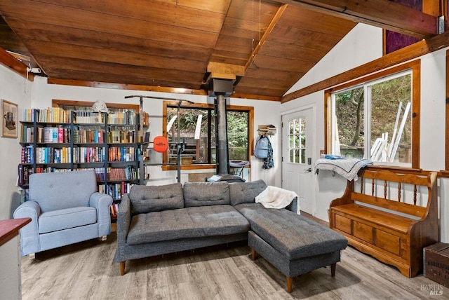 sitting room with vaulted ceiling with beams, wood ceiling, a healthy amount of sunlight, a wood stove, and wood finished floors