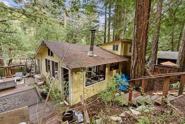 rear view of property with a shingled roof and a deck