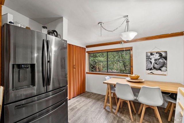 kitchen featuring vaulted ceiling, light wood finished floors, stainless steel refrigerator with ice dispenser, and decorative light fixtures