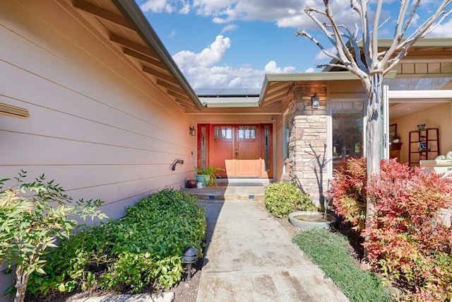 view of exterior entry featuring stone siding and roof mounted solar panels