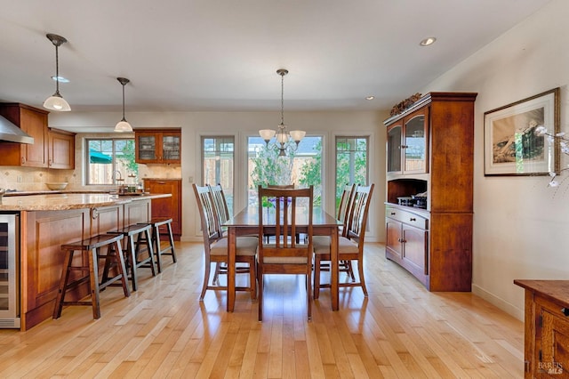 dining space with a wealth of natural light, wine cooler, and light wood-style flooring