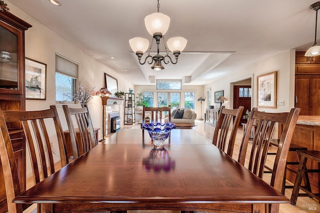 dining room featuring a healthy amount of sunlight, light wood-style flooring, and an inviting chandelier