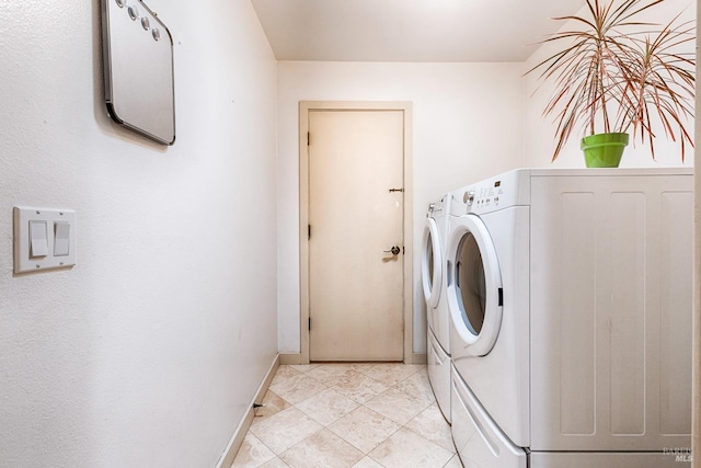 clothes washing area featuring laundry area, baseboards, and washer and clothes dryer