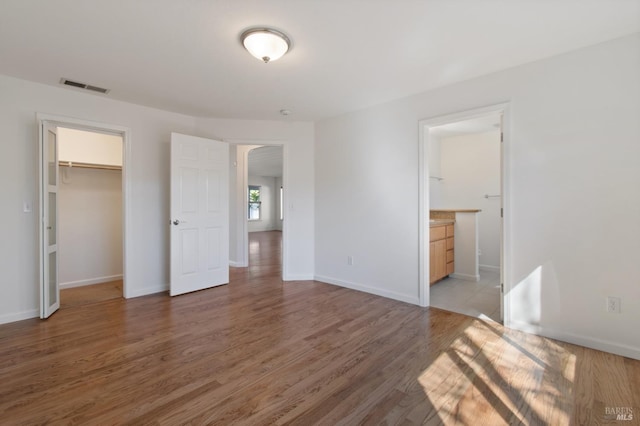 unfurnished bedroom featuring a closet, light wood-type flooring, visible vents, and baseboards