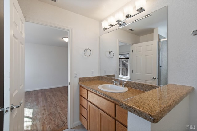 bathroom with baseboards, visible vents, wood finished floors, and vanity