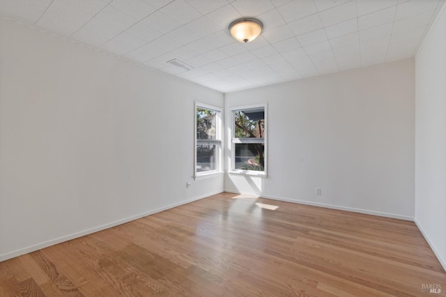 spare room featuring light wood-style floors, visible vents, and baseboards