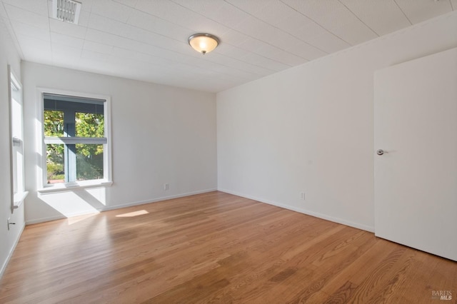 unfurnished room with light wood-type flooring, visible vents, and baseboards