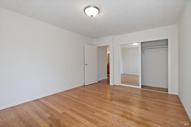 unfurnished bedroom with light wood finished floors, a closet, and baseboards