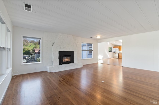 unfurnished living room featuring a fireplace, visible vents, and wood finished floors