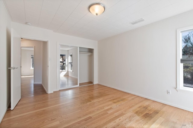 unfurnished bedroom with visible vents, a closet, light wood-style flooring, and baseboards