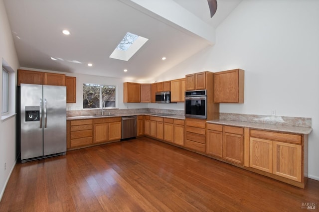 kitchen featuring dark wood-style floors, a skylight, recessed lighting, appliances with stainless steel finishes, and a sink