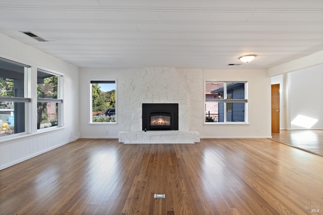 unfurnished living room featuring baseboards, a fireplace, visible vents, and wood finished floors