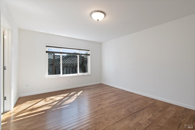 empty room featuring wood finished floors and baseboards