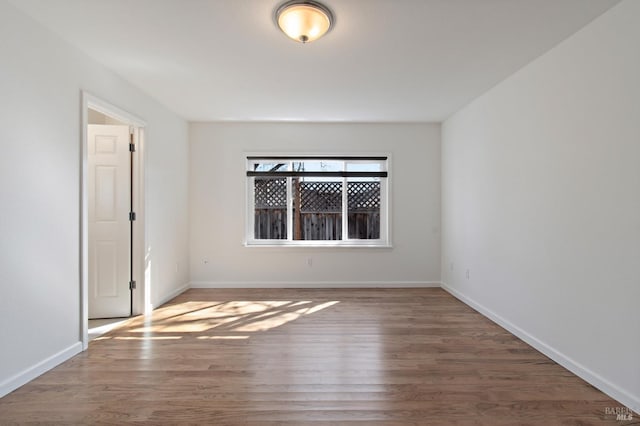 unfurnished room with baseboards and wood finished floors