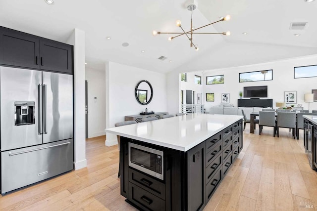 kitchen with stainless steel appliances, open floor plan, dark cabinetry, and visible vents