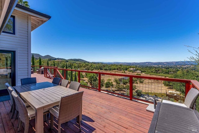 wooden terrace featuring a mountain view and outdoor dining space