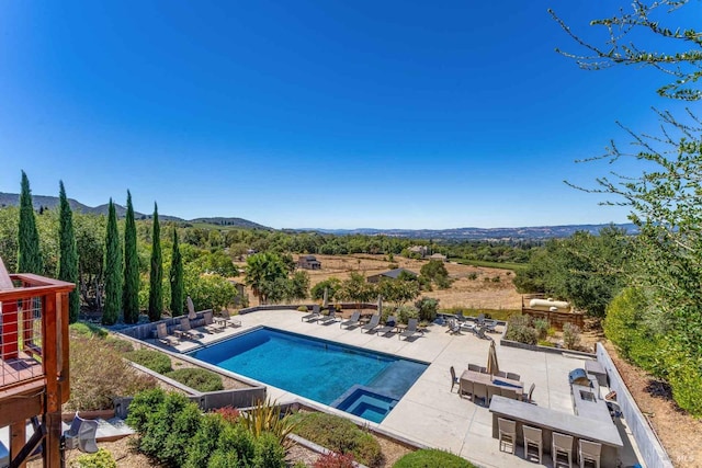 outdoor pool with a mountain view and a patio