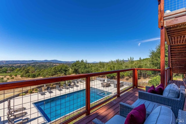 wooden deck featuring a fenced in pool and a view of trees