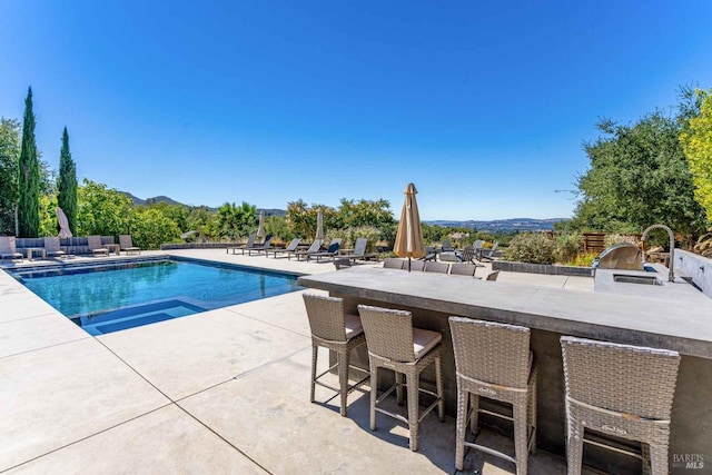 view of swimming pool with a patio, outdoor wet bar, a sink, exterior kitchen, and a fenced in pool