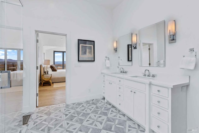 bathroom with a sink, double vanity, connected bathroom, and baseboards