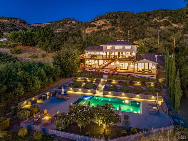 rear view of house with a fire pit, an outdoor pool, stairs, a wooden deck, and a patio area