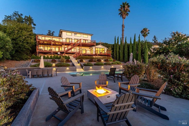 view of patio with stairway, an outdoor pool, and a fire pit